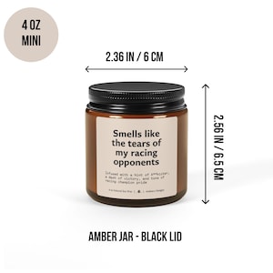 May include: An amber glass candle jar with a black lid, containing a 4 ounce candle. The label reads "Smells like the tears of my racing opponents". The jar measures 6 cm wide and 6.5 cm tall.