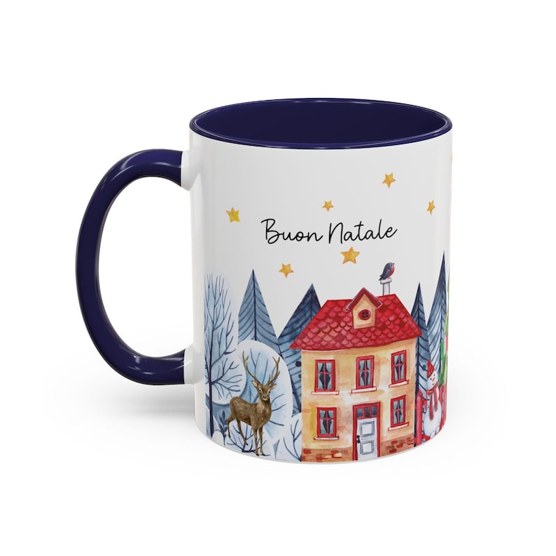 May include: White ceramic mug with a blue rim and handle. The mug features a watercolor illustration of a winter village scene with a house, trees, a deer, and a snowman. The text "Buon Natale" is printed on the mug.