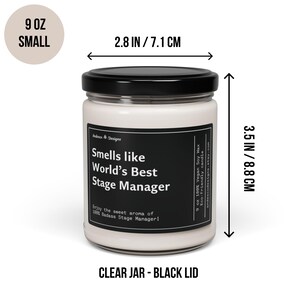 May include: A 9 ounce soy wax candle in a clear glass jar with a black lid. The candle is labelled "Smells like World's Best Stage Manager". The jar is 7.1 cm wide and 8.8 cm tall.