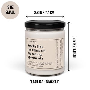 May include: A 9 ounce soy wax candle in a clear glass jar with a black lid. The candle is labelled "Smells like the tears of my racing opponents." The label also includes the text "Infused with a hint of A**kicker, a dash of victory, and tons of racing champion pride." The candle is 8.8 cm tall and 7.1 cm wide.