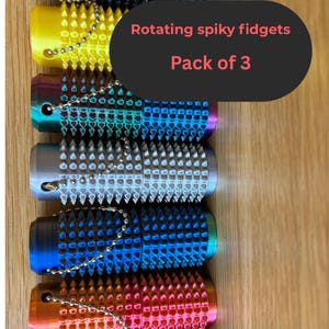 May include: A pack of three rotating spiky fidgets in various colors, including black, yellow, teal, silver, blue, and orange. Each fidget has a textured, spiky surface and a small chain for attachment.