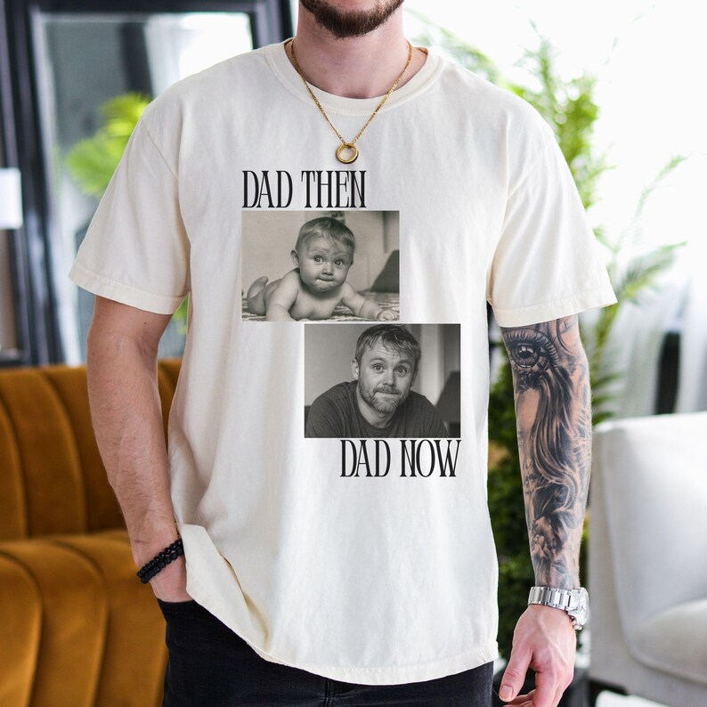 May include: Cream-colored t-shirt featuring two black and white photos. The top photo shows a baby, and the bottom photo shows an adult man. The words "DAD THEN" and "DAD NOW" are printed above and below the photos.