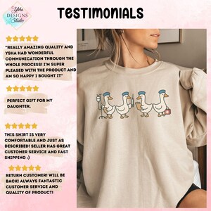 May include: Beige sweatshirt featuring a line of cartoon geese dressed as medical professionals. The geese are wearing blue hats and carrying medical equipment. The word "Testimonials" is at the top of the image, along with customer reviews.