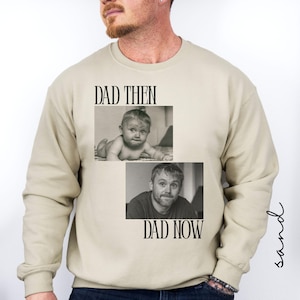 May include: Sand-colored sweatshirt with the text "DAD THEN" and "DAD NOW" above and below two black and white photos. The top photo shows a baby, and the bottom photo shows an adult man.
