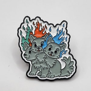 Puede incluir: Un pin de un lobo gris de tres cabezas con llamas naranjas, azules y verdes detrás. El lobo tiene un contorno blanco y ojos negros.