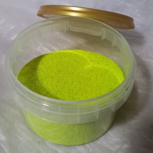 May include: A clear plastic container with a gold lid filled with bright green glitter.