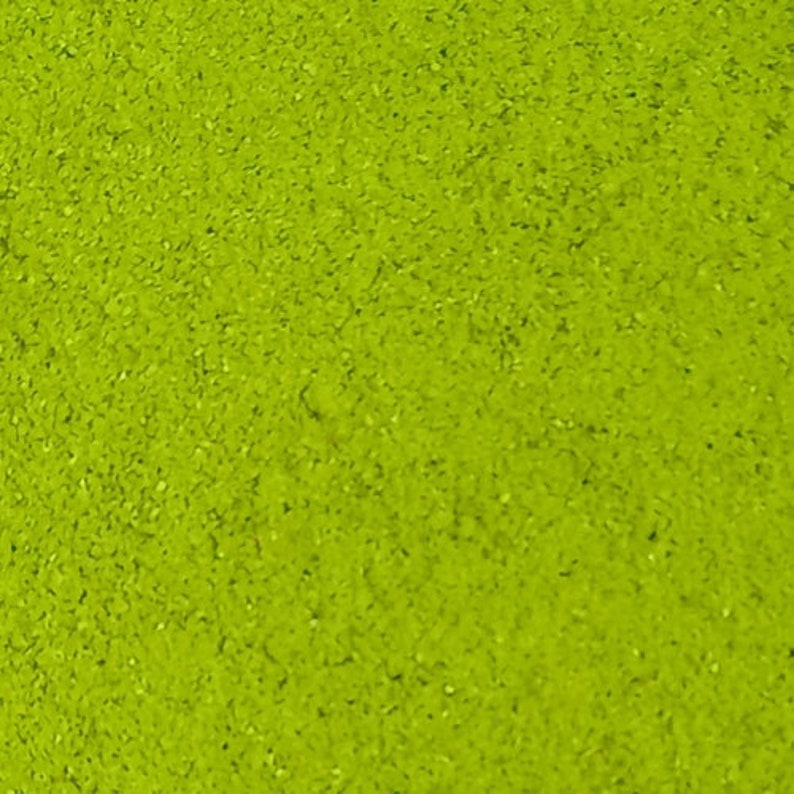 May include: A close-up of a bright green powder, possibly matcha or another type of green tea powder.