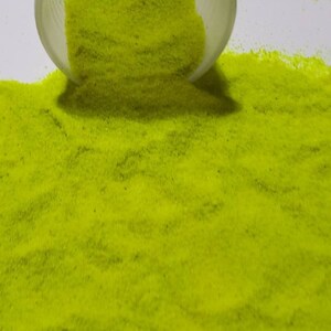 May include: A close-up of a pile of bright yellow glitter sand. The sand is fine and sparkly, and it is perfect for crafts or decorations.