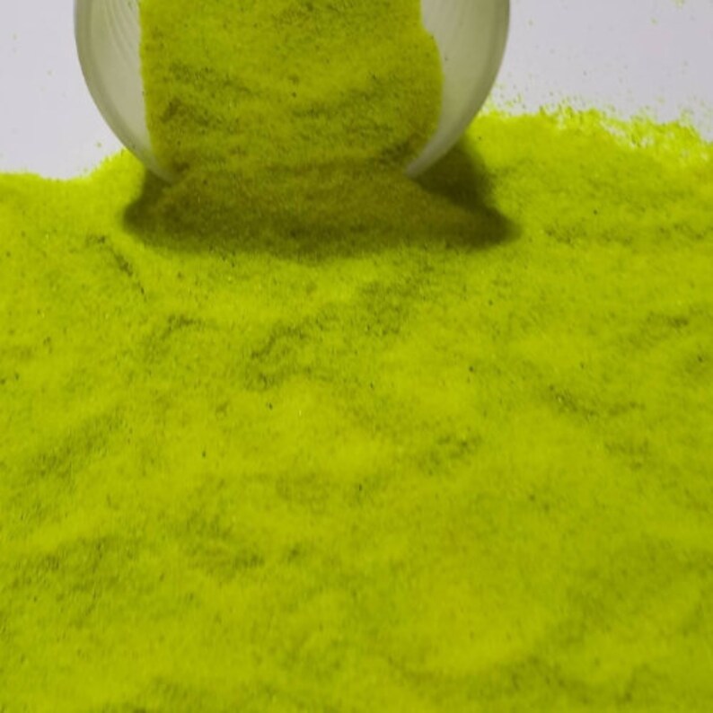 May include: A close-up of a pile of bright yellow glitter sand. The sand is fine and sparkly, and it is perfect for crafts or decorations.