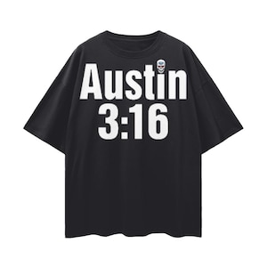 May include: Black short-sleeved t-shirt with the text "Austin 3:16" in large white letters across the front. A small skull graphic with a blue and white design is on the upper right. The shirt has a casual, oversized fit.