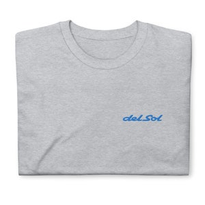 May include: A gray t-shirt with a blue embroidered logo that says "del Sol".