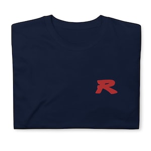 Könnte beinhalten: Ein marineblaues T-Shirt mit einem roten stilisierten Buchstaben "R" auf der rechten Brustseite.