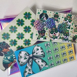 May include: Four different sticker sheets featuring a variety of designs. The first sheet has a pattern of green four-leaf clovers on a white background. The second sheet has a pattern of green bows with four-leaf clovers on a yellow, green, and blue gradient background. The third sheet has a pattern of green four-leaf clovers on a white background. The fourth sheet features a variety of dogs wearing green hats and holding candy canes. The text "$25 Total" is in the bottom right corner of the sheet.
