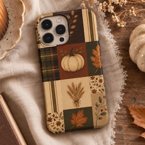 May include: A rectangular phone case featuring a patchwork design of autumn-themed illustrations. The pattern includes a cream-colored pumpkin, a bundle of wheat, maple leaves, floral motifs, and plaid sections in shades of brown, tan, and green.