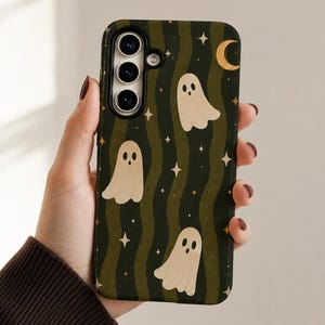 May include: A rectangular smartphone case featuring a dark green and olive wavy striped background. The design includes multiple cream-colored ghost illustrations with simple facial features, interspersed with small yellow four-pointed stars and a crescent moon.