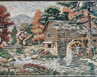 Puede incluir: Una obra de arte en mosaico que representa un molino de agua de madera rústico con una rueda de agua, rodeado de árboles y un arroyo que fluye. La escena se desarrolla en un bosque con un pequeño puente y una montaña en el fondo.