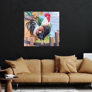 May include: A colorful painting of a rooster standing on a fence. The rooster is black, white, and red with a large red comb. The background is a blurred image of a farm scene.