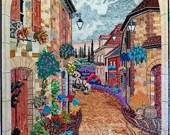 Puede incluir: Una obra de arte en mosaico que representa una calle estrecha y adoquinada en un pueblo europeo. La calle está bordeada de edificios coloridos y vegetación exuberante, creando una escena encantadora y pintoresca.