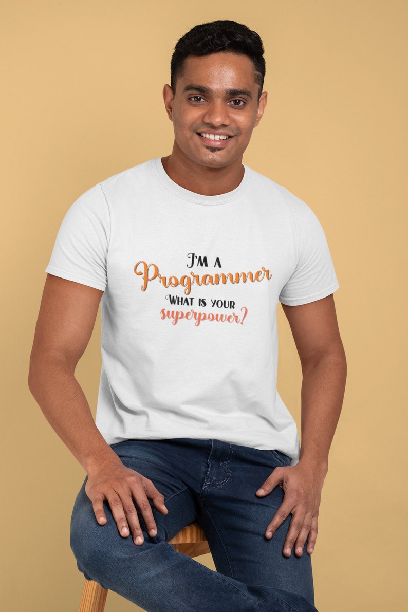 以下が含まれることがあります： オレンジと黒で「I'm a Programmer. What is your superpower?」と書かれた白いTシャツです。
