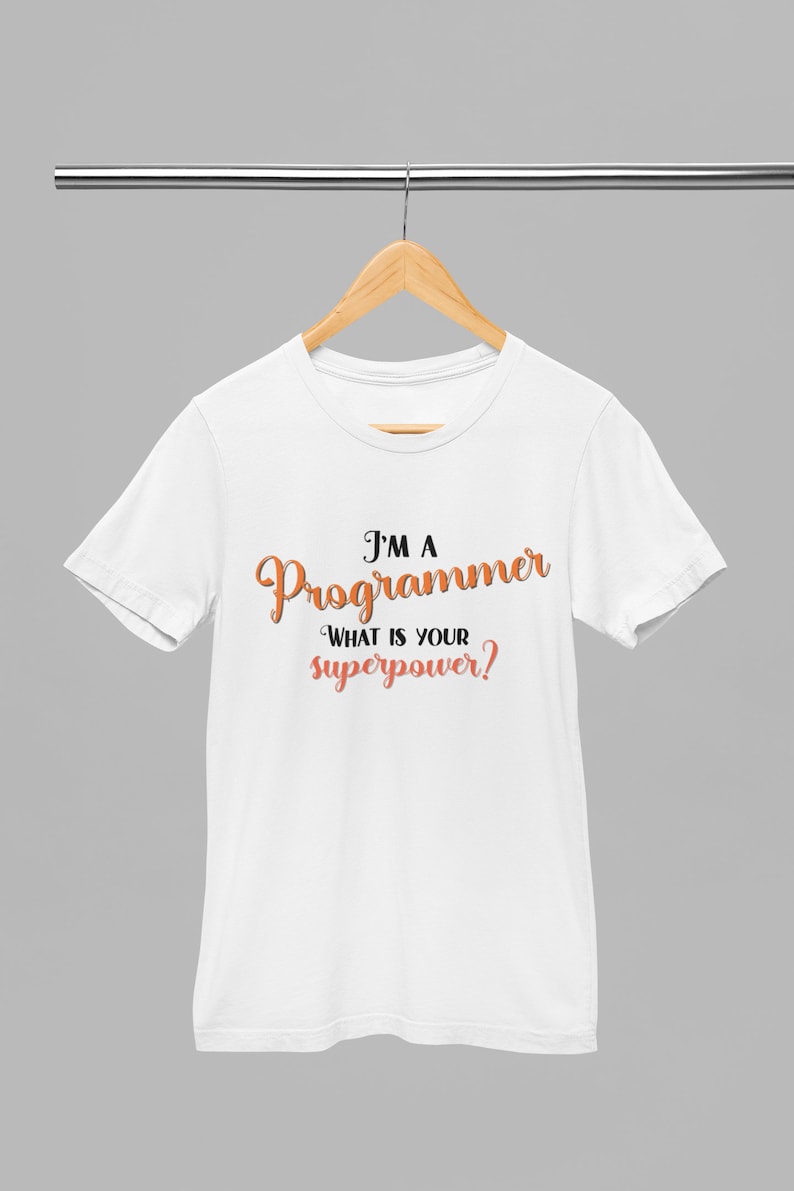 以下が含まれることがあります： 黒い文字とオレンジ色の文字で「I'm a Programmer What is your superpower?」と書かれた白いTシャツです。