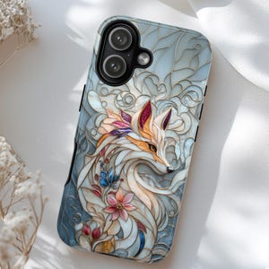 May include: A phone case featuring a stained glass style design of a fox surrounded by floral elements. The artwork uses a palette of cream, light blue, pink, and purple with gold outlines. The case has a black camera cutout for two lenses.