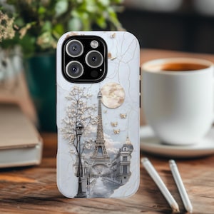 May include: White iPhone case featuring a detailed image of the Eiffel Tower, a tree, and a moon. The case has a white marble-like background with gold accents.