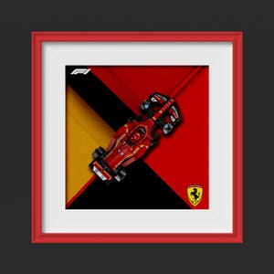 May include: Framed print featuring a red Formula 1 race car on a geometric background of red, black, and yellow. The Ferrari logo is visible in the lower right corner. The frame is red.