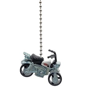 May include: A silver and white motorcycle fan pull with a black seat and a silver chain.