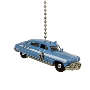 May include: A blue and white 1950s era police car with a silver chain hanging from the roof. The car has the words "Midtown County Police" on the side and "RADIO CAR 1" on the door.