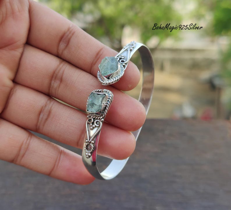 Puede incluir: Pulsera de brazalete de plata con dos acentos de piedras preciosas verde claro. La pulsera tiene un dise&ntilde;o delicado y adornado.