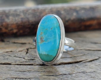 May include: A turquoise oval ring set in sterling silver. The turquoise is a vibrant blue-green color with brown veins.