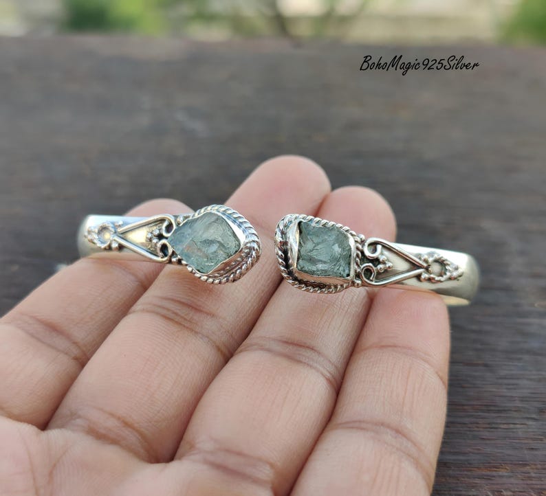 Puede incluir: Pulsera de brazalete de plata con dos piedras preciosas de aguamarina. La pulsera tiene un dise&ntilde;o delicado y adornado con un patr&oacute;n de cuerda trenzada.