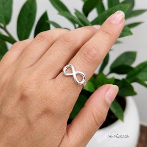 May include: A polished silver ring featuring an infinity symbol design centered on the band. The metal has a smooth, reflective finish and the infinity loop is positioned horizontally across the finger. The text "Boho Magic 925 Silver" is visible.