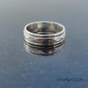May include: A silver ring with a hammered texture. The ring is wide and has a rounded shape.