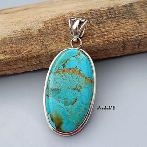 May include: A turquoise oval pendant with a silver setting. The pendant has a unique marbled pattern and is suspended from a silver bail.