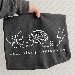 Può includere: Una tazza di ceramica bianca con manico nero e la scritta "But First, Coffee" in nero, in grassetto. La tazza è appoggiata su una superficie di legno. La tazza è alta circa 10 cm.