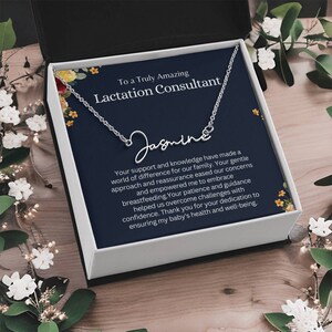 May include: A silver necklace with a personalized nameplate that reads "Jasmine" in cursive script. The necklace is displayed in a gift box with a message thanking a lactation consultant for their support and knowledge.