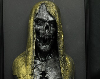 May include: A 3D printed sculpture of a hooded figure with a skull-like face, painted in black and gold. The figure is framed and appears to be a horror or fantasy themed art piece.