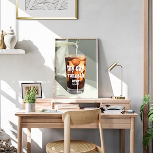 Pu&ograve; includere: Una stampa incorniciata di un bicchiere di caff&egrave; freddo con il testo "my cup runneth over" in lettere bianche. La stampa &egrave; su uno sfondo verde chiaro e si trova su una scrivania di legno.