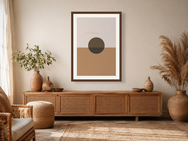 May include: A framed wall art print featuring a split-color background with a light beige upper half and a tan lower half. A dark charcoal circle is centered at the horizon line. The print is enclosed in a dark brown frame with a white mat border.