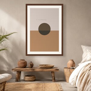 May include: A framed wall art print featuring a horizontal split composition with a light beige upper section and a solid tan lower section. A dark brown circle is centered over the horizon line, and a small row of birds is visible in the sky.