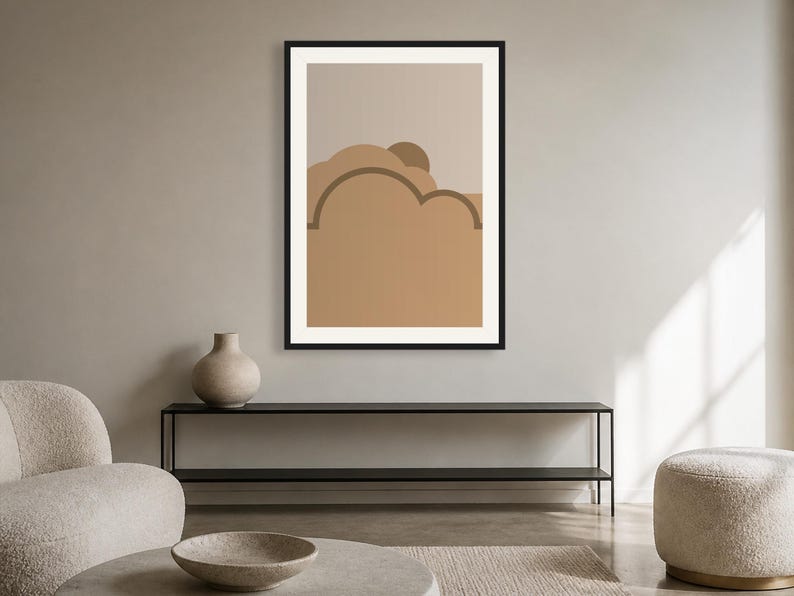 May include: A framed wall art print featuring a graphic illustration of layered, rounded shapes in shades of tan, beige, and brown. The artwork is enclosed in a thin black frame and displays a stylized landscape composition with curved lines.