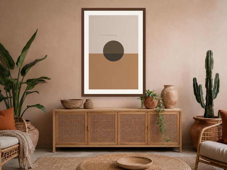 May include: A framed wall art print featuring a horizontal split design with a light beige upper section and a solid terracotta lower section. A dark brown circle is centered over the horizon line, with small, thin black horizontal lines above it.