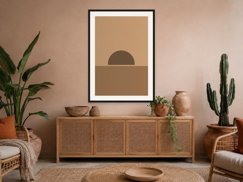 May include: A framed wall art print featuring a minimalist graphic design of a dark brown semi-circle sun positioned above a solid medium brown horizontal line, set against a light tan background within a thin black rectangular frame.