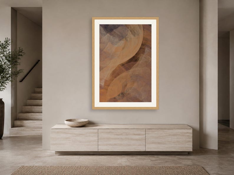May include: A vertical framed wall art piece featuring an abstract composition of overlapping, translucent curved shapes in shades of warm tan, deep brown, and muted gray, enclosed within a light-colored wooden frame and a white mat border.