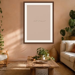 May include: A rectangular wall art print featuring a minimalist design with a solid light beige background and a small, dark horizontal line of tiny bird silhouettes centered in the middle, enclosed within a simple dark brown wooden frame.