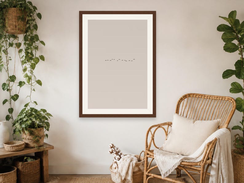 May include: A rectangular wall art print featuring a minimalist beige background with a small, centered horizontal line of tiny dark birds in flight, enclosed within a thick, dark brown wooden frame hanging on a plain wall.
