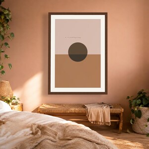 May include: A framed wall art print featuring a horizontal split composition with a light beige upper section and a solid tan lower section. A dark brown circle is centered over the horizon line, with a small line of tiny black birds above it.