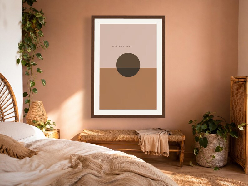 May include: A framed wall art print featuring a horizontal split composition with a light beige upper section and a solid tan lower section. A dark brown circle is centered over the horizon line, with a small line of tiny black birds above it.