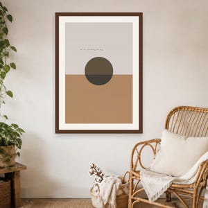 May include: A framed wall art print featuring a split-tone design with a light gray upper section and a solid tan lower section. A dark brown circle is centered over the horizontal line, and a small line of tiny black birds is visible above.